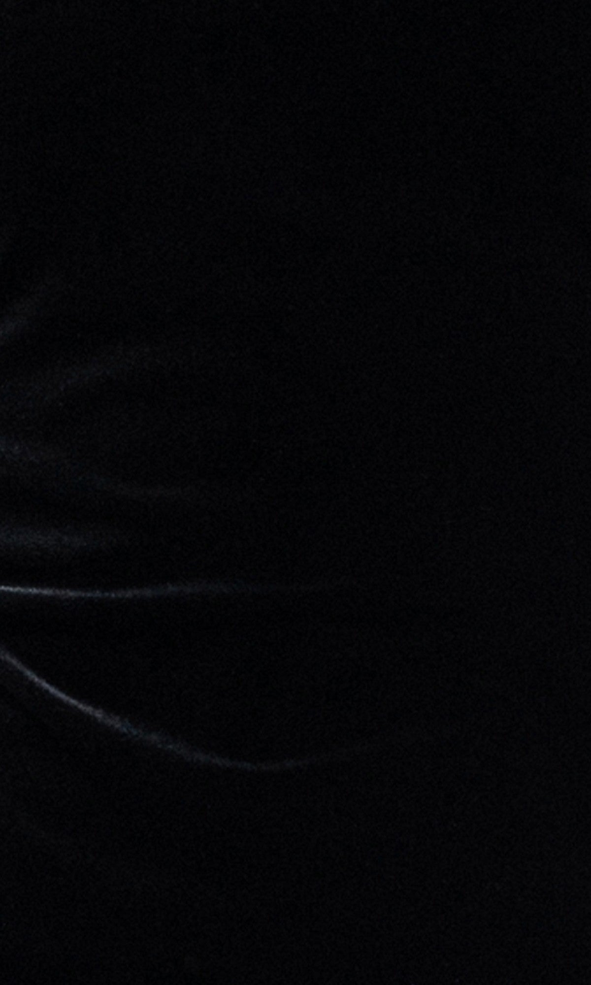 A dark surface with subtle, wavy light reflections and faint highlights evokes the soft texture of the Blondie Nites 6381BN Long Sleeve Mini Hoco Dress, featuring delicate feathered cuffs, creating an elegant and sophisticated backdrop that complements this affordable black homecoming dress.